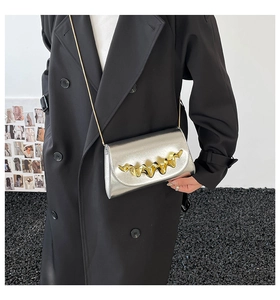 Détail du sac bandoulière argenté métallisé avec boucle dorée et fine chaîne