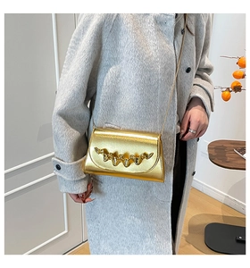 Détail du sac à chaîne doré avec accent ondulé sur mannequin en manteau gris