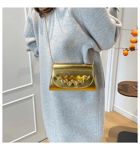 Détail d'un sac à bandoulière doré chic avec chaîne sur un manteau d'hiver gris chiné