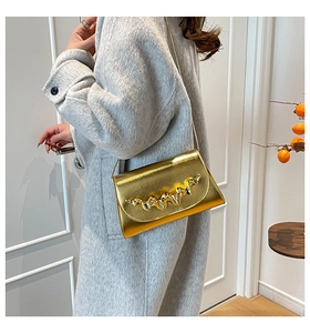 Détail du sac à bandoulière doré avec bordure ondulée sur un manteau en laine gris
