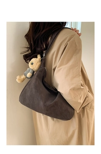 Detail of dark brown faux leather hobo bag featuring a cute plush bear charm accessory