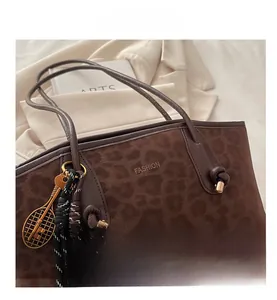 Détail du sac cabas léopard avec pendentif raquette dorée et poignée en cuir nouée