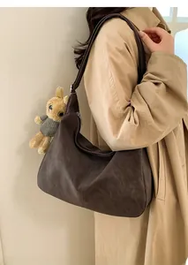 Borsa tote in pelle marrone scuro con ciondolo a coniglietto di peluche portata a spalla