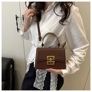 Dettaglio della borsa a tracolla in pelle marrone con fibbia geometrica dorata elegante