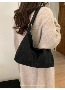 Macro detail of black suede shoulder bag with minimalist retro hobo style and silver buckle