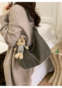 Detail of soft olive green oversized shoulder bag with a plush rabbit charm accessory