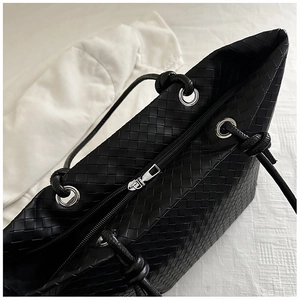 Close-up of black woven tote bag with silver metal zipper and intricate texture