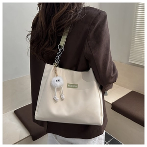 Détail du sac fourre-tout blanc cassé avec bandoulière verte et breloque peluche monstre
