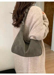 Detail of grey-green hobo bag with wide strap on model in beige knit sweater