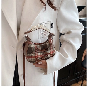 Dettaglio della mini borsa a quadri con fiocchi in pelle e pizzo su blazer bianco
