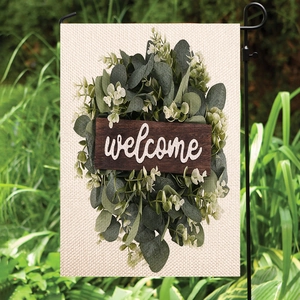 Outdoor linen welcome garden flag featuring eucalyptus leaves pattern on a black metal stand