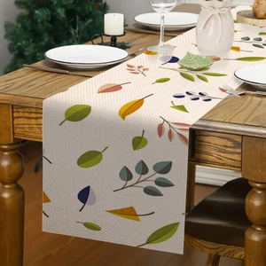 Dettaglio runner da tavola in lino con foglie colorate di eucalipto su tavolo in legno