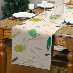 Dettaglio runner da tavola in lino con foglie di eucalipto su tavolo di legno