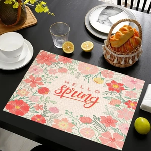 Detail van een linnen placemat met bloemenprint en de tekst Hello Spring op tafel