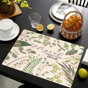 Detail of linen placemat featuring green plant prints and Elegant Greenery text on a table