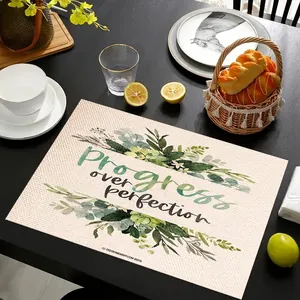 Linen placemat with floral design and Progress over perfection quote on a dark table