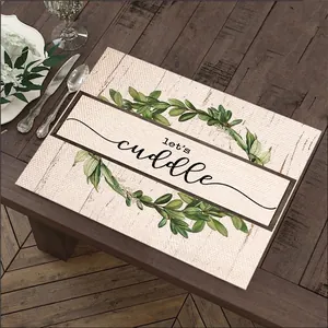 Linen placemat with green botanical wreath and Let's Cuddle text on wooden table