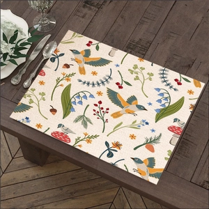 Linen placemat with floral and bird prints on a rustic wooden dining table setting