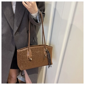 Détail du cabas léopard avec texte argenté et pendentif tissé sur la bandoulière de sac
