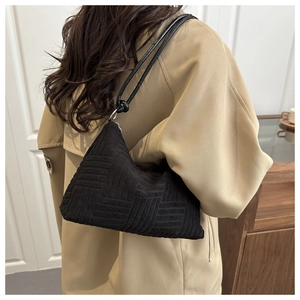 Dettaglio della borsa nera con trama geometrica indossata su un trench color kaki