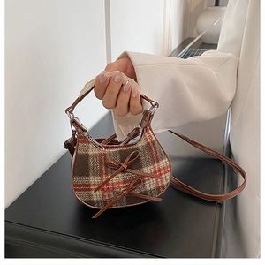 Dettaglio mini borsa a quadri con fiocchi in pelle e manico decorato con pizzo bianco