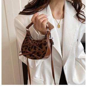 Dettaglio mini borsa a mezzaluna leopardata con finiture in pelle e fiocchi decorativi
