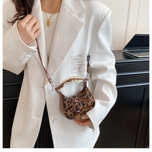 Mini borsa a tracolla leopardata con fiocchi indossata su un blazer bianco