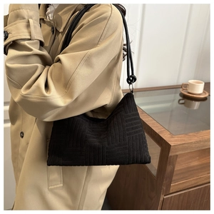 Dettaglio della borsa a spalla in maglia nera con trama geometrica in stile moderno