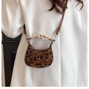 Dettaglio mini borsa leopardata con fiocchi e pizzo indossata su un blazer bianco casual