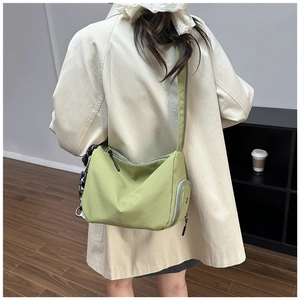 Moderno bolso bandolera de nylon verde hierba visto de espaldas en trench beige