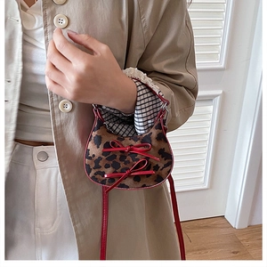 Dettaglio mini borsa leopardata con fiocchi in pelle rossa e finitura testurizzata
