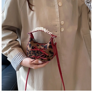 Dettaglio mini borsa leopardata con fiocchi in pelle rossa e manico rifinito in pizzo