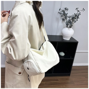 Primer plano de bolso bandolera minimalista de lona beige con bolsillo lateral y correa