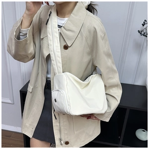 Detalle del bolso bandolera de nailon blanco roto con correa ancha de cremallera y bolsillo