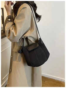 Détail du sac seau noir mat avec breloque latérale et fine bandoulière élégante