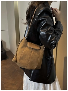 Close-up of brown suede shoulder bag with patchwork design and tassel on a female model
