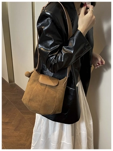 Sac hobo en daim marron porté à l'épaule avec une finition minimaliste en cuir mat