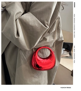 Dettaglio mini borsa laccata rossa con catena dorata su un trench classico