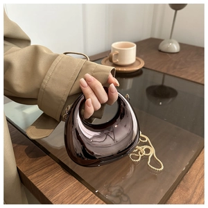 Dettaglio della mini borsa a mezzaluna creativa con finitura a specchio grigia lucida