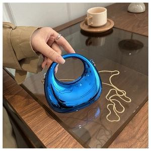 Dettaglio borsa a mezzaluna blu cromato con finitura lucida e catena dorata