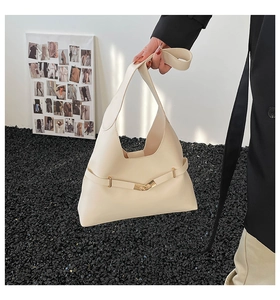 Dettaglio della borsa a mezzaluna color crema con cintura sottile e fibbia dorata