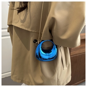 Borsa a mezzaluna blu con catena dorata indossata da modella in trench