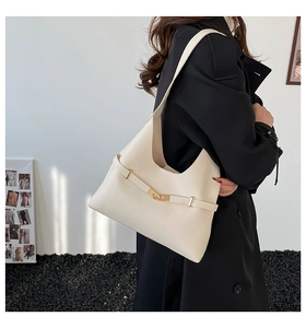 Dettaglio borsa hobo crema con fibbia dorata indossata da modella con cappotto nero