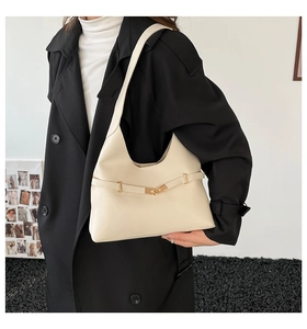 Dettaglio della borsa beige con fibbie dorate e sottile cinturino in pelle