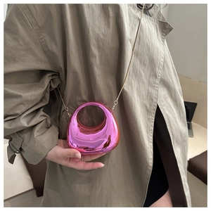 Dettaglio di pochette rosa a specchio con manico rotondo e catena d'oro su trench