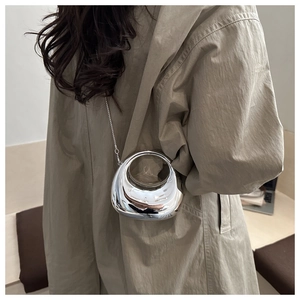 Mini borsa a mezzaluna argento a specchio con catena in acrilico su trench kaki