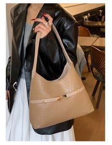 Detail van beige bucket bag met krokodillenprint en gouden gesp op een model