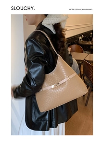 Detail of a beige woven slouchy shoulder bag featuring a metal buckle and textured finish