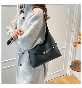 Dettaglio borsa a mezzaluna in pelle nera con fibbia dorata indossata su cappotto grigio