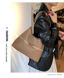 Close-up of brown woven texture handbag with beige leather strap and gold buckle